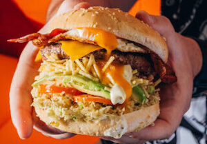 Persona con una hamburguesa de QW Food Truck