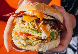 Persona con una hamburguesa de QW Food Truck